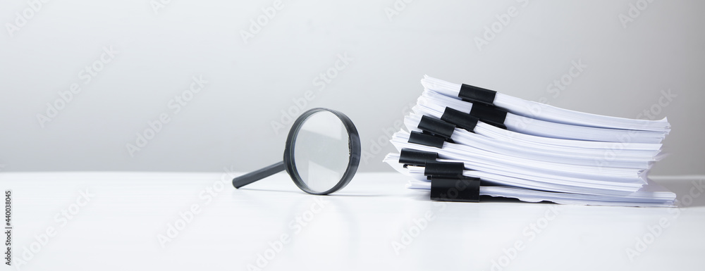 Aufkleber stack of report paper documents with magnifying glass.