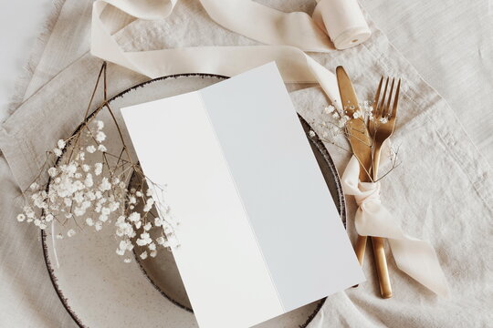 Menu card mockup on empty modern minimal table place setting neutral beige color top view.  Space for text. Sheet card template, wedding invitation. Scandinavian style.