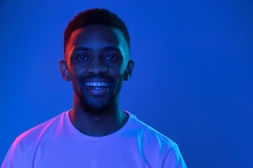 African-american young man's portrait on dark studio background in neon. Concept of human emotions,...
