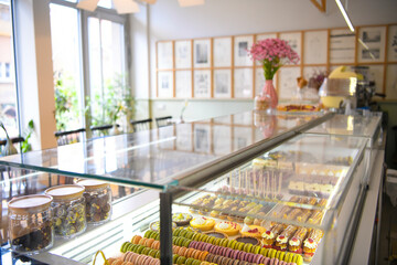 Pastry shop glass display with selection of sweets and cakes. Confectionery shop display background. Delicious sweet treats variety. Small buisness concept.