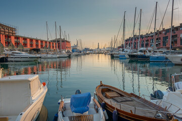 View of the old port of Genoa at sunset with boats and Lanterna lighthouse, Italy.