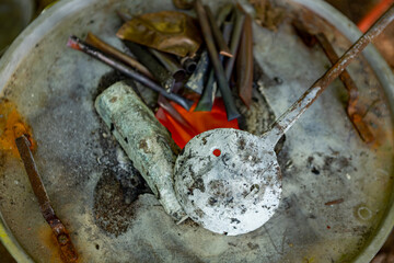 Texture and detail of raw material around orange and red tones of super heated mix of metals tin and copper in special furnace construction. Bronze casting process and manual labor concept.
