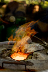 Aggressive orange and red tones flame of super heated mix of metals tin and copper in special furnace construction. Bronze casting process.