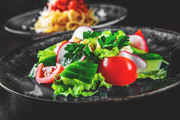 Salad with cucumber, tomato, red onion, pepper, parsley and Feta cheese on black background