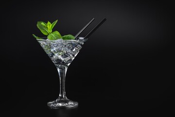 The best cocktail in a martini glass with ice and mint on a black background, top view, black...