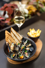 Boiled mussels in copper cooking dish on dark wooden background close up