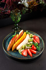 The concept of a healthy diet. Platter fruits and berries - apple, orange, banana, kiwi, strawberry, mint