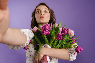 White smiling woman taking selfie while holding tulips