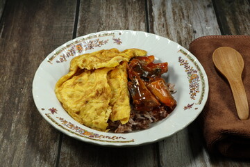 Easy street food menu in Asia. Fried egg and mackerel in tomato sauce topping on cooked rice. Low cost meal.