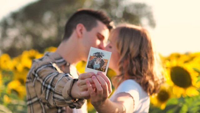 Pareja besandose mientras sostienen una foto de ellos