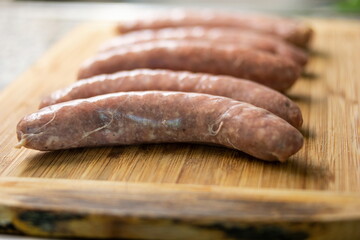 Fresh raw Italian sausages on a wooden kitchen board close up shot top view no people