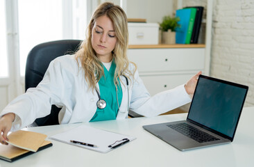Female doctor working on medical consultation and treatment information on laptop at hospital office