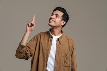 Brunette hispanic man in shirt smiling and pointing finger upward