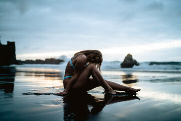 Chica veraniega guapa en una playa de arena negra durante el atardecer luciendo su bikini de moda