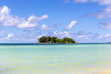 Uninhabited tropical island Chauve Souris protruding from Indian Ocean, with turquoise water around and crystal blue sky seen from Cote d'Or beach on Praslin, Seychelles.