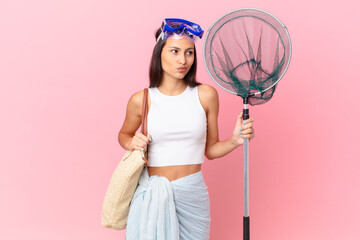 young fisher woman shrugging, feeling confused and uncertain and and diving goggles