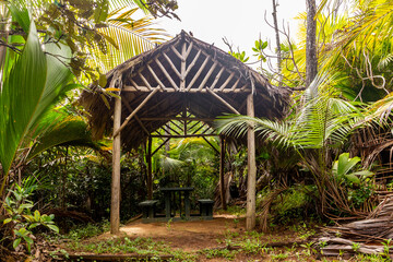 Wooden shelter with thatched roof made of palm leaves in tropical rainforest on Glacis Noire Nature...