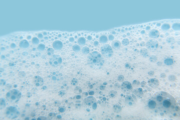 White cosmetics foam texture on blue background. Cleanser, shampoo bubbles, wash - liquid soap, shower gel, shampoo. Texture of white foam on rose background. Cosmetics banner with copy space.