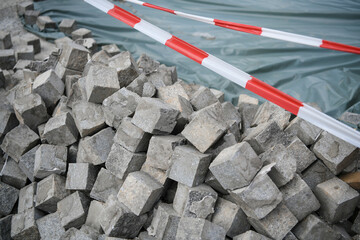 Pellet with  many small granite block cobblestone paving stones, stacked, ready to be used on a construction site, a road and sidewalk renovation site. Construction zone.