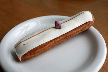 Eclair with glaze on white plate
