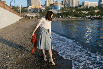 Woman in dress enjoys the sea shore.