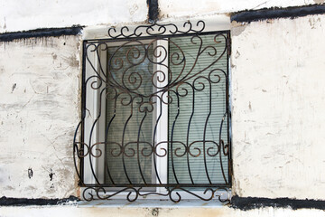 A metal lattice on a window in a city house.