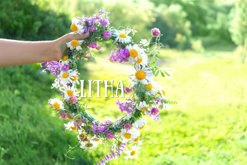 Litha holiday concept. floral wreath in hand, sunny natural background. flower crown, traditional...