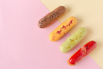 Eclairs on a minimal background. Still life hello dessert mood. Traditional French dessert with colorful icing. Concept baking, cookbook recipes, bakery banner, cafe advertisement.