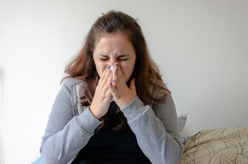 latin woman feeling sick, pain, illness, sneezing using tissue to cover nose