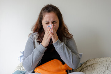 latin woman feeling sick, pain, illness, sneezing using tissue to cover nose