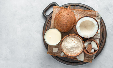 Fresh coconut and coconut products: milk and flour on a gray background.
