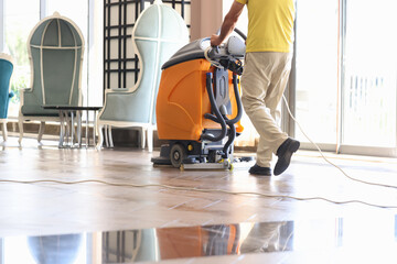 Janitor is cleaning hall with washing vacuum cleaner closeup