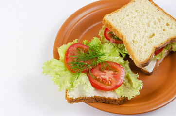Vegetable Sandwiches and brown clay plate on white background. Square sandwiches with tomato, lettuce, dill, sauce.