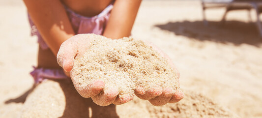 Closeup of little girl hands holding sand on beach