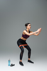 Obraz premium sportswoman doing sit ups with resistance band on grey background.
