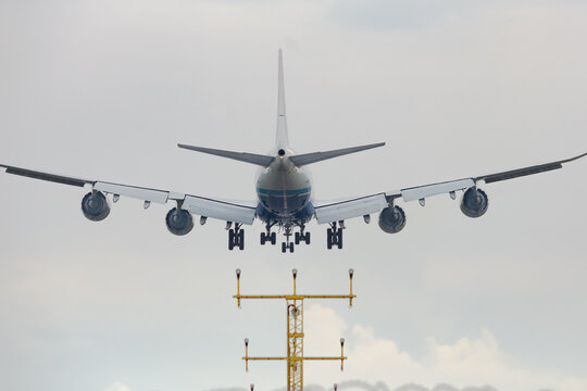 Big cargo aircraft is landing on the airstrip of Milan Malpensa Airport, Italy. Wings, fuselage and engine are visible. Sky with clouds in the background.
