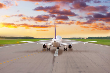 Passenger plane on the runway ready to take off in the evening at sunset sky.