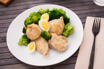 pieces of fried chicken breast with boiled broccoli and quail eggs on plate for lunch