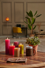 Colorful candle close up concept with coffee wicker glass on the wooden desk, decorative working table computer and chair lamp background.