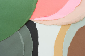 torn paper composition arranged with negative white space for text - in green grey black pink and...