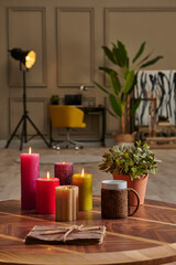 Colorful candle close up concept with coffee wicker glass on the wooden desk, decorative working table computer and chair lamp background.