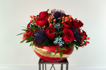Red and blue color floral arrangement on white background. Holiday table centerpice. Valentine flowers. Red roses blue carnations tropical protea. 