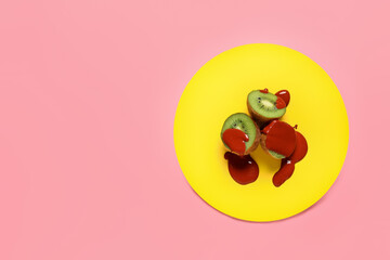 Ripe kiwi with drops of paint on color background