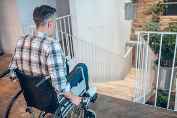 View back of a man in wheelchair near stairs