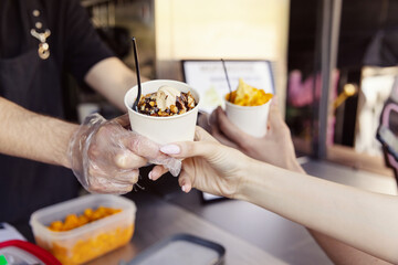 Obraz na płótnie Canvas Human hand holding cone with twisted ice cream from machine