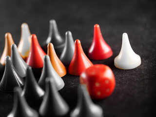 Grayscale shot of board game pieces next to dice on the floor with some of them colored