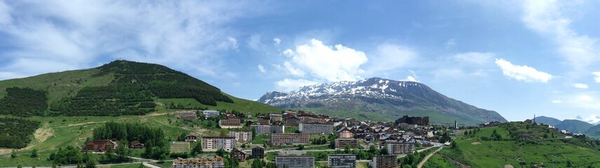 Fototapeta na wymiar Panoramique de l'Alpe d'Huez en Oisans, la station et les pistes de ski en été avec un drone