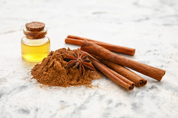 Cinnamon oil, sticks and powder on light background