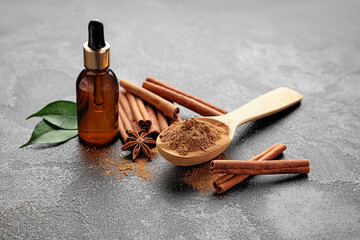 Cinnamon oil, sticks and powder on grey background