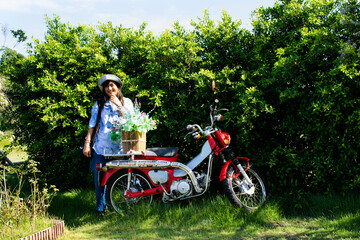Asian traveler thai women travel visit and posing portrait with  classic vintage retro red motorcycle in gardening garden backyard outdoor of cafe and restaurant coffee shop in Nakhon Pathom, Thailand - Powered by Adobe
